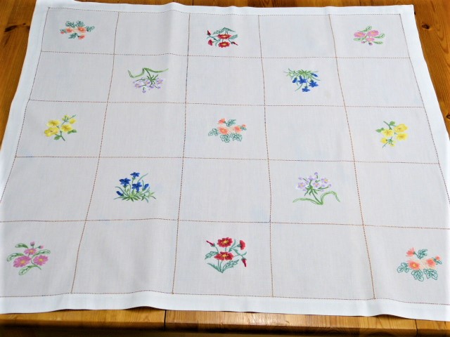 Weiße Mitteldecke durch Hohlsaum in Quadrate aufgeteilt mit Blumenmotiven ausgefüllt 80x85